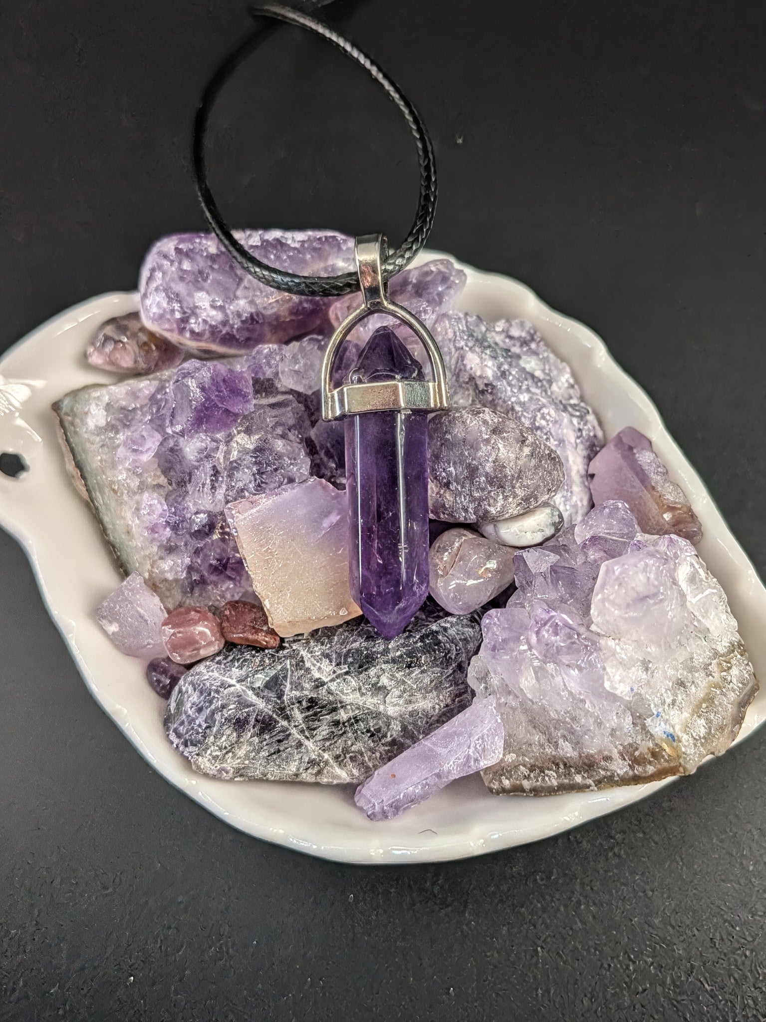 Amethyst crystal pendant on a black background with amethyst stones