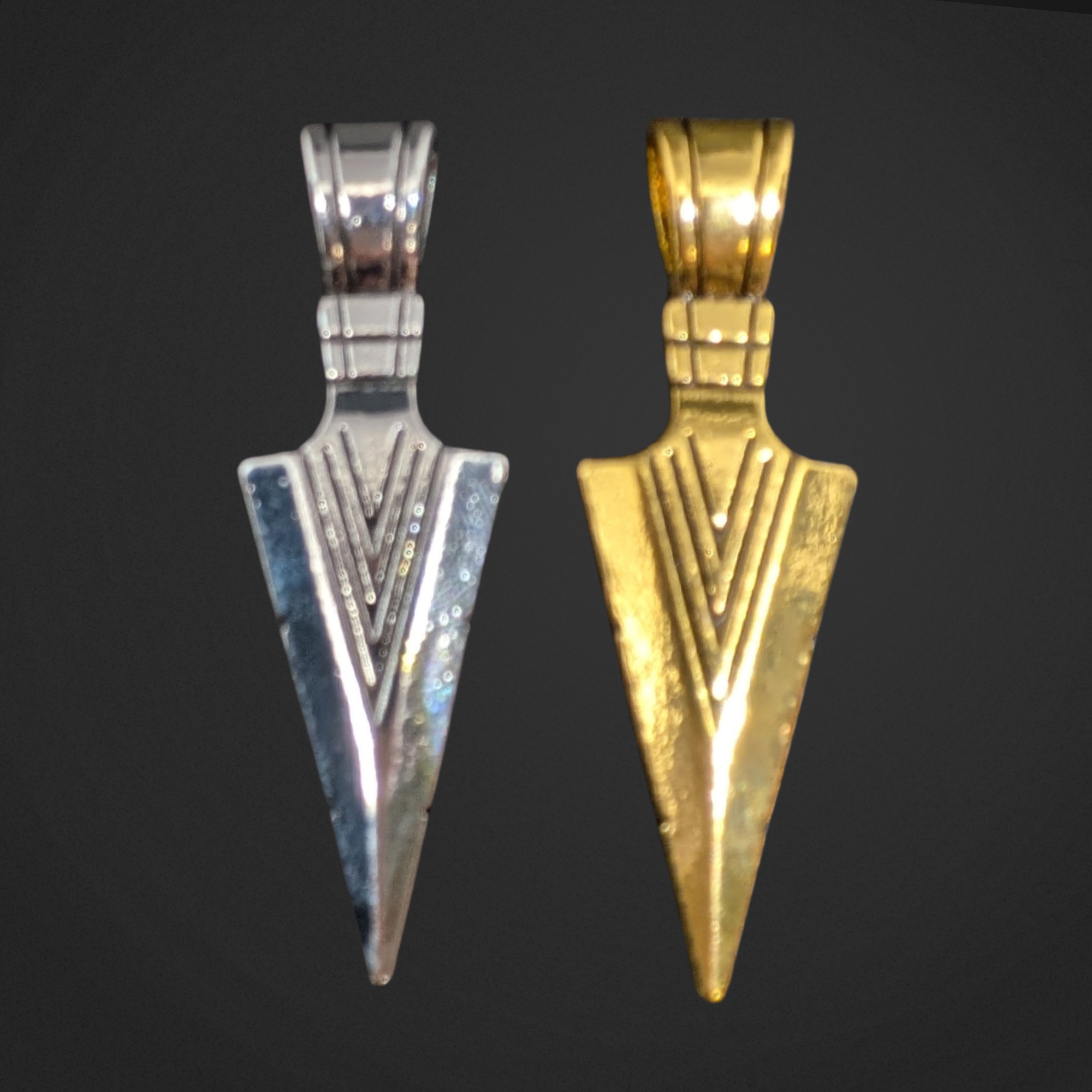Silver and gold arrowhead-shaped pendants on a black background