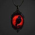 Pendant with a black bird silhouette on a red background against a dark background