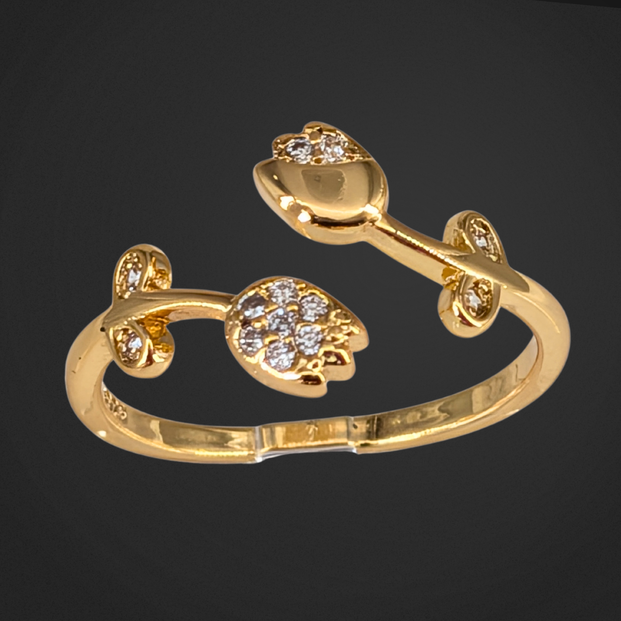 Gold bracelet with floral design and clear stones on a black background