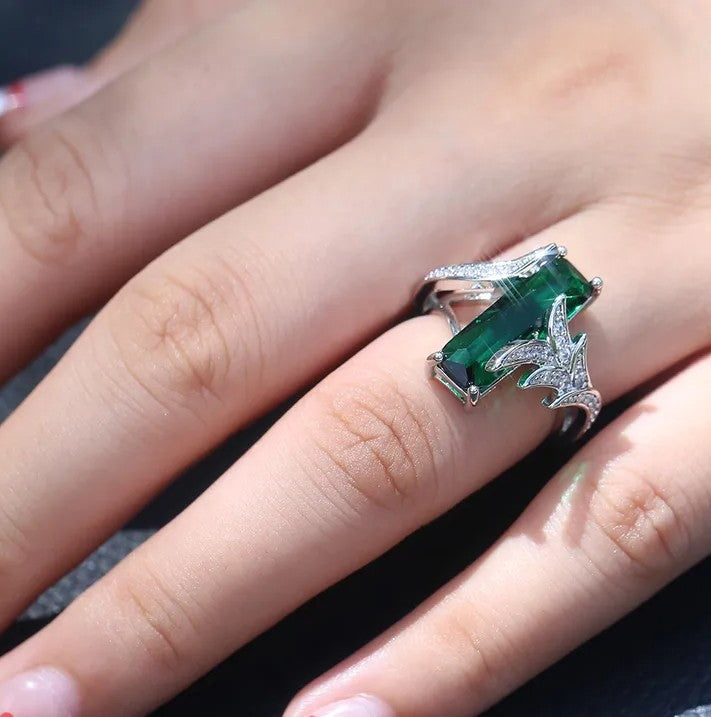 Green gemstone ring with silver band on a hand