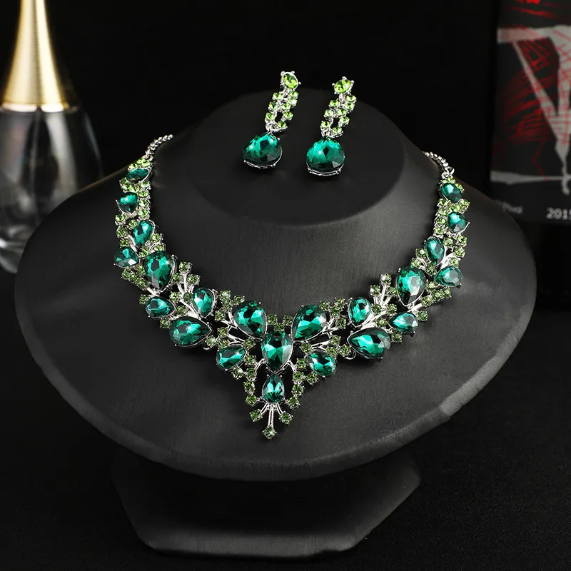 Green gemstone necklace and earrings on a black stand with a dark background