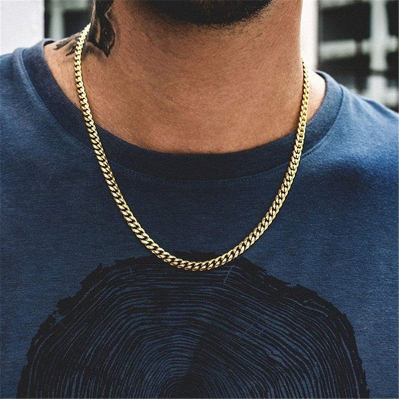 Gold chain necklace worn by a person on a blurred background