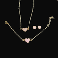Gold necklace with pink heart pendants and matching earrings on a black background