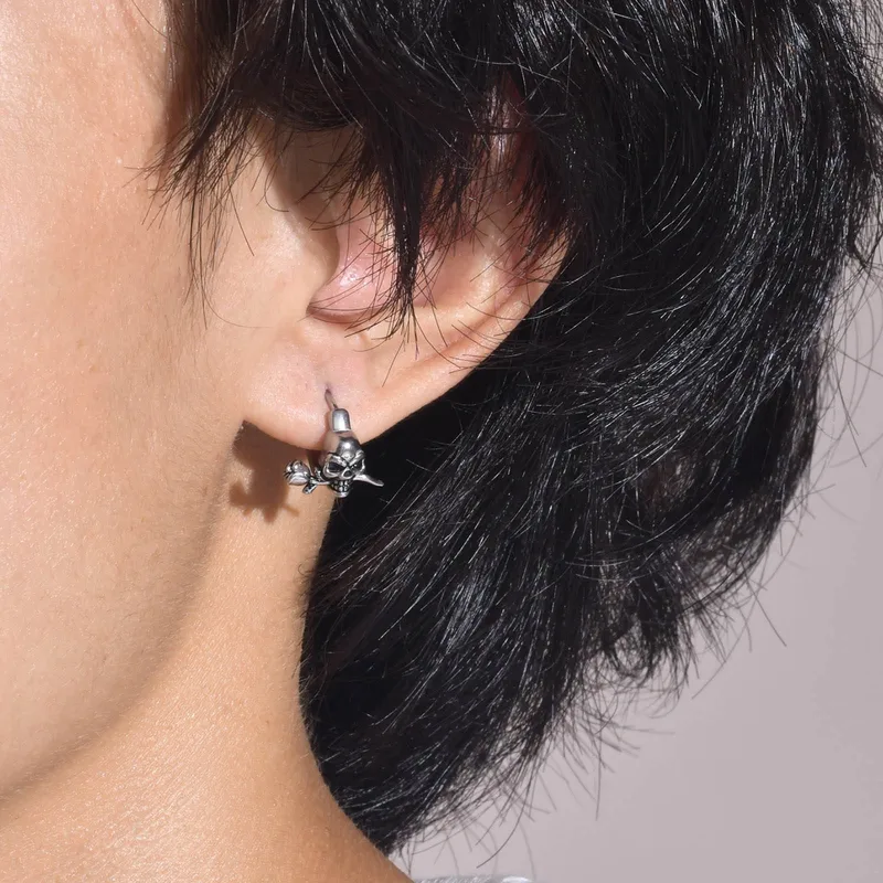 Close-up of an ear wearing a silver earring with a neutral background