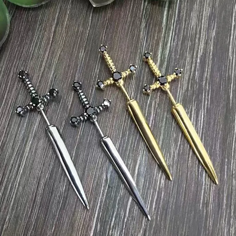 Four decorative sword earrings with black gemstones on a wooden surface
