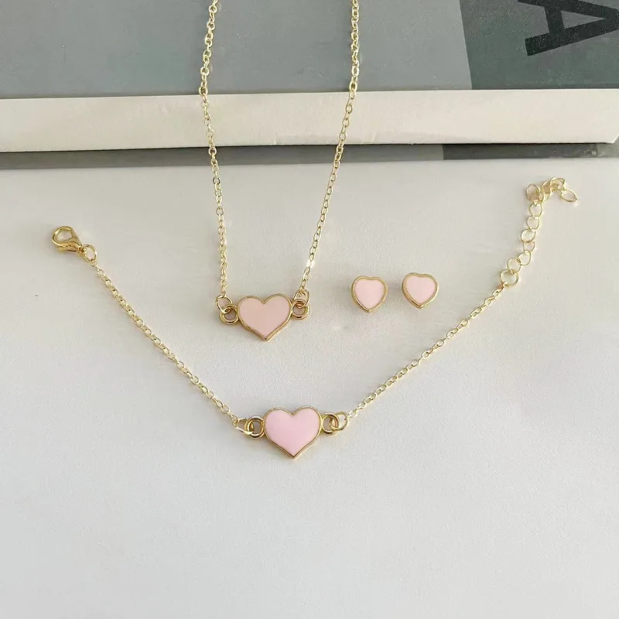 Jewelry set with pink heart-shaped pendants on a white surface