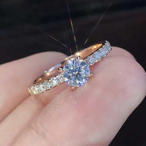 Diamond ring with a large central gemstone and smaller diamonds on a finger against a dark background