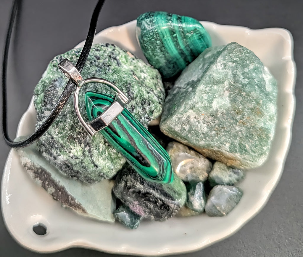 Malachite pendant on a necklace with malachite stones on a white dish