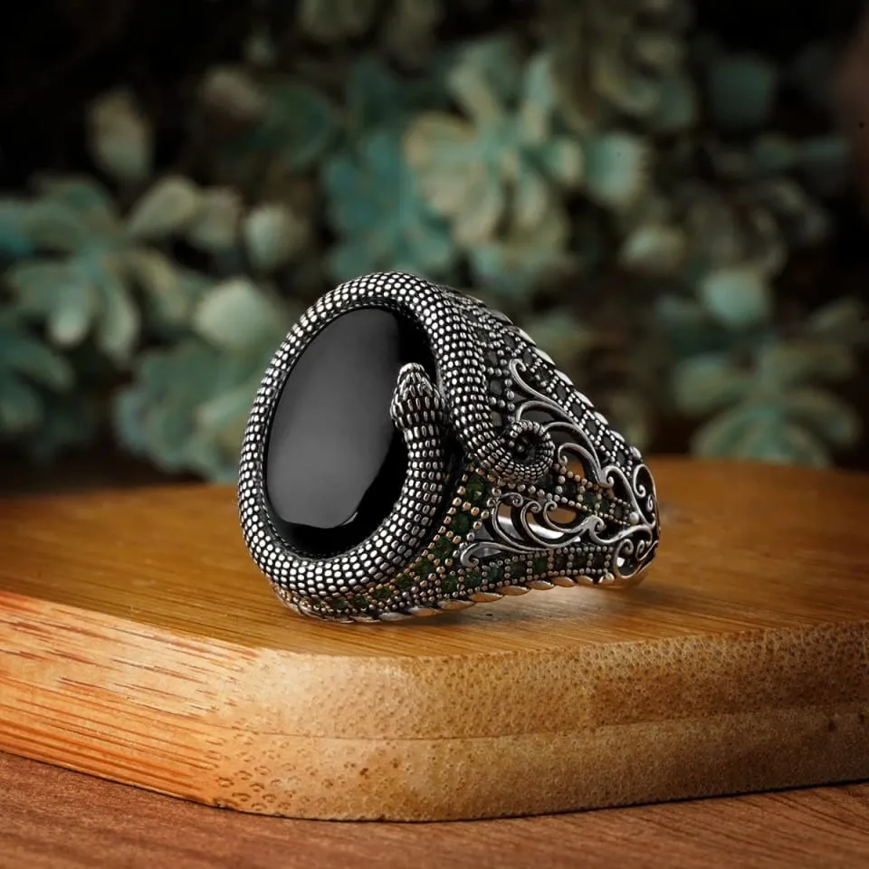 Decorative ring with black stone on a wooden surface with blurred greenery in the background