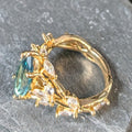 Gold ring with a green gemstone and smaller diamonds on a gray background
