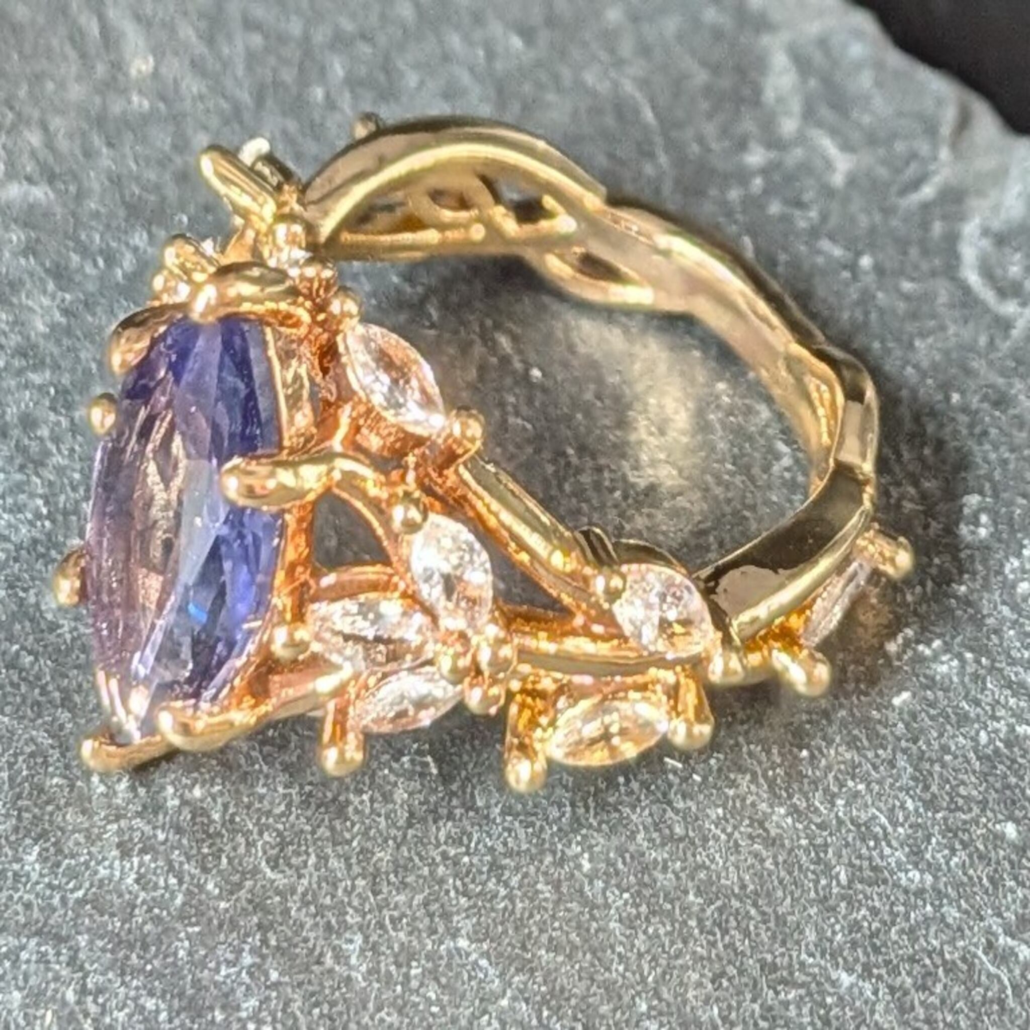 Gold ring with a purple gemstone on a gray surface