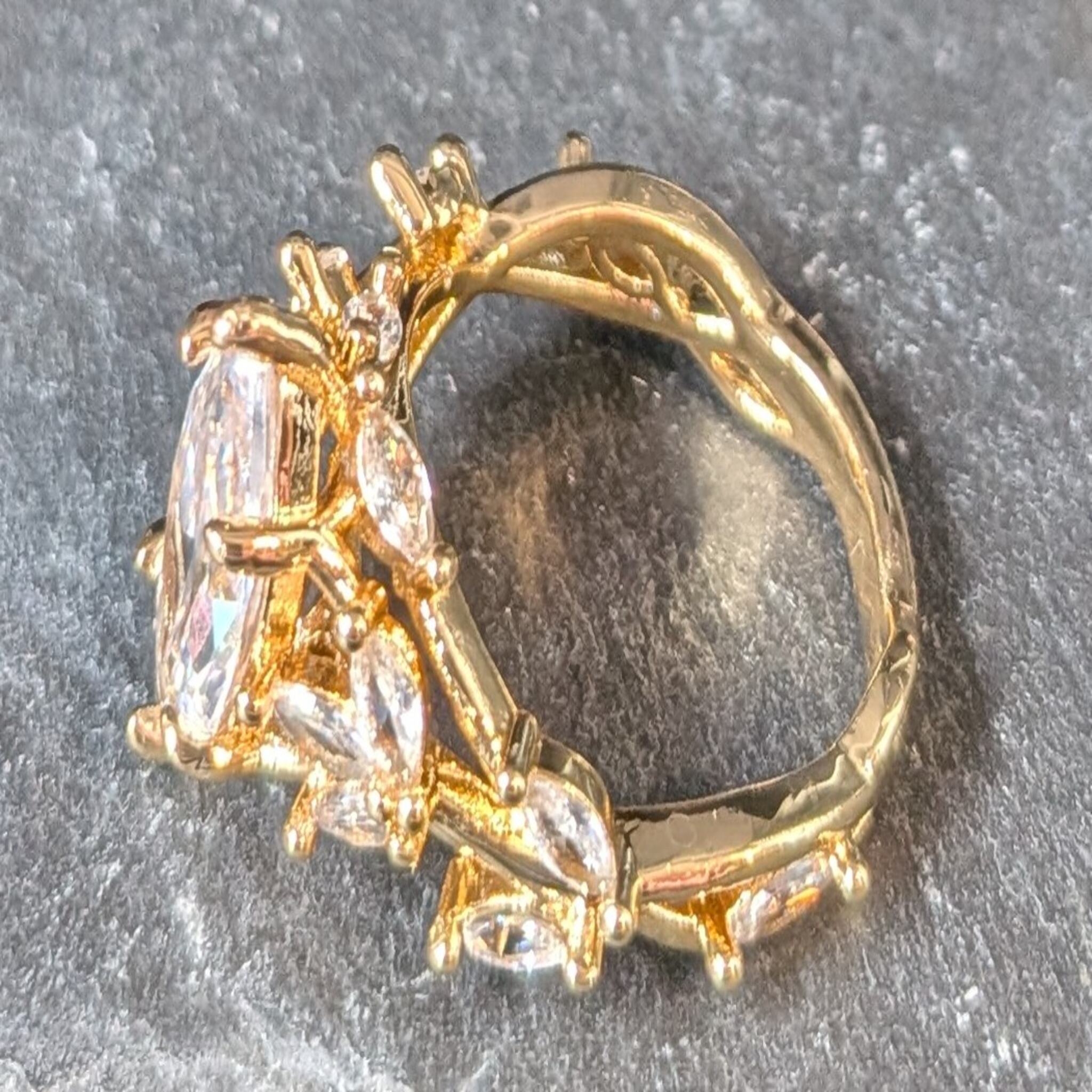 Gold ring with diamond-like stones on a gray surface