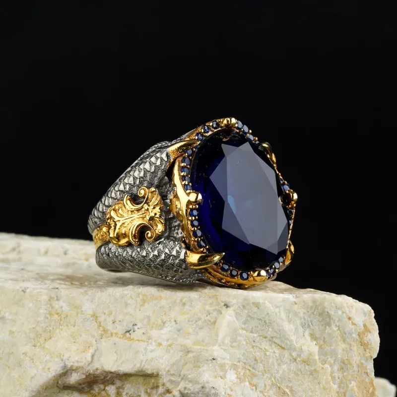Gold and silver ring with a large blue gemstone on a stone surface