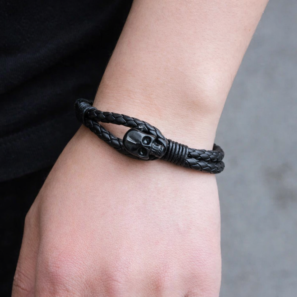 Black braided bracelet with skull design on a wrist against a neutral background