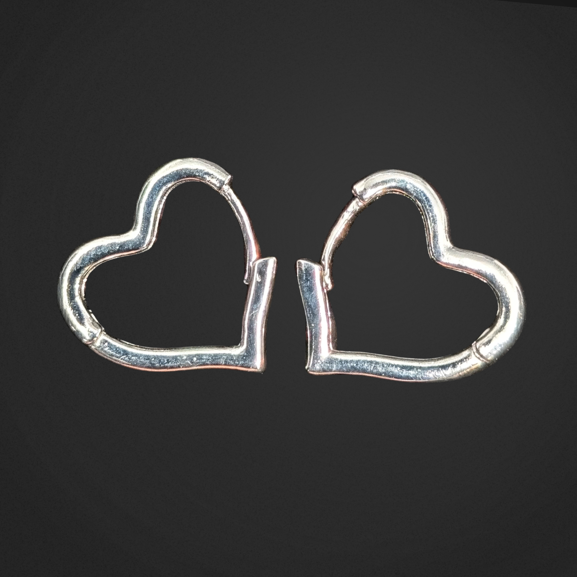 Heart-shaped silver earrings on a black background