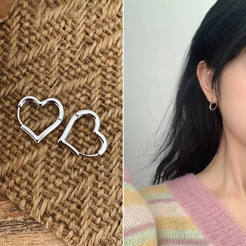 Heart-shaped earrings on a textured surface and a person wearing them.