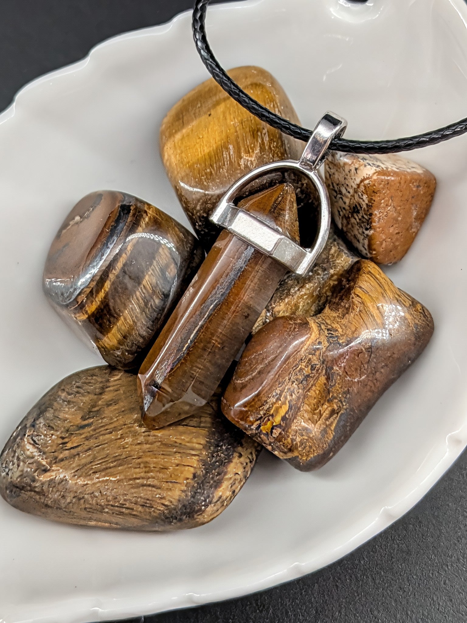 Tiger's eye stone pendant on a white dish with a dark background