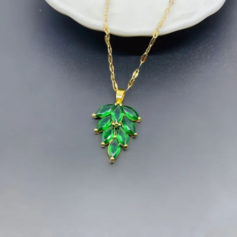 Green leaf-shaped pendant on a gold chain against a gray background