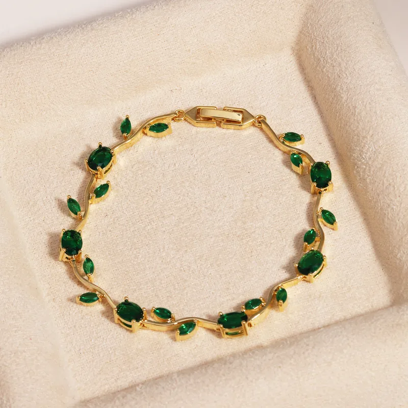 Gold bracelet with green gemstones on a beige surface