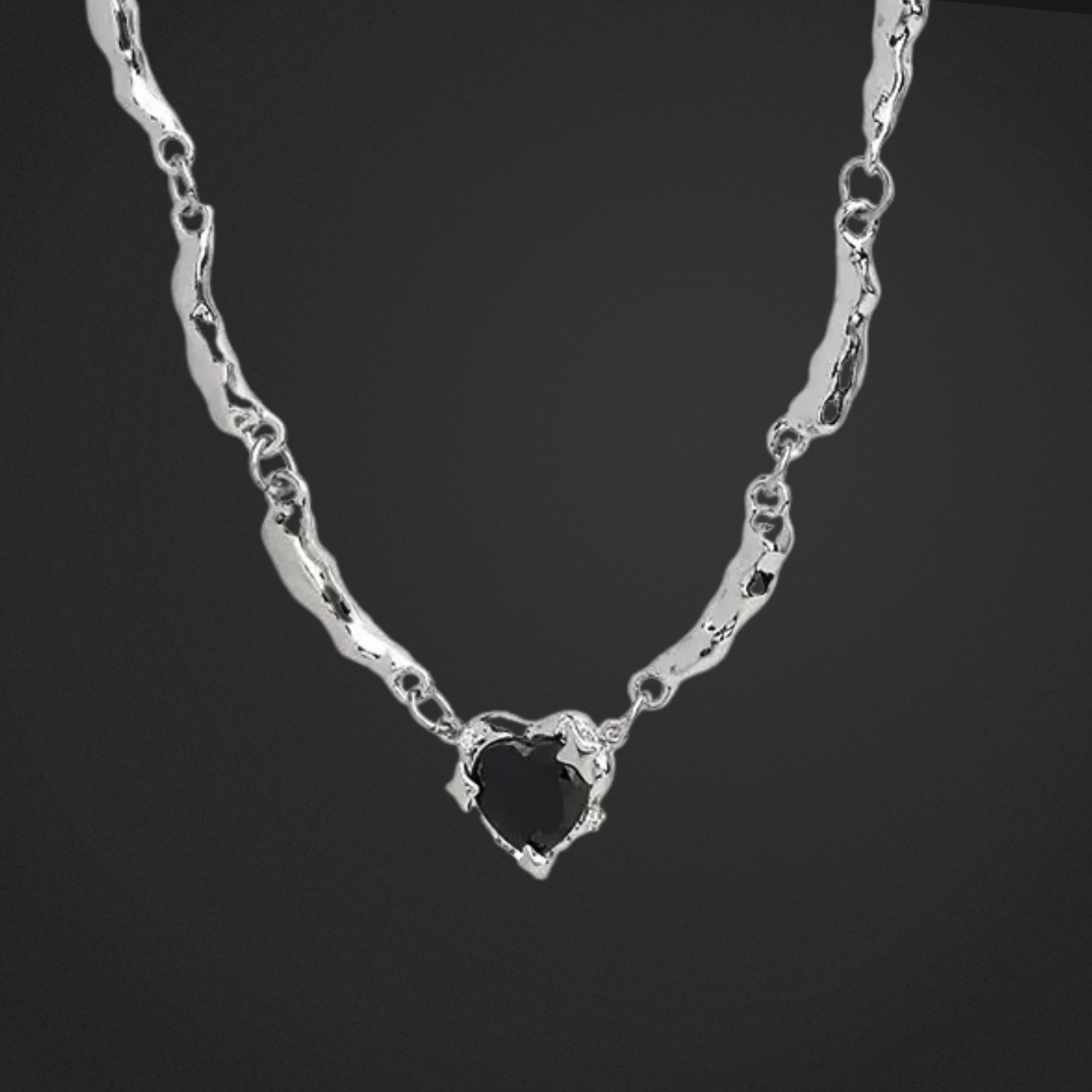 Silver necklace with a heart-shaped pendant on a black background