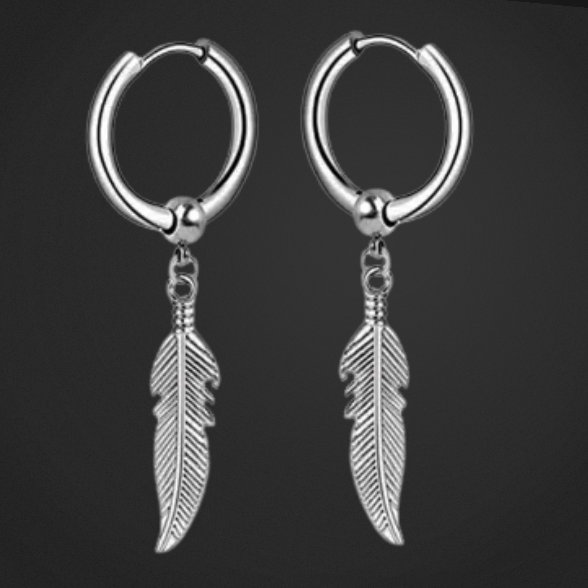 Pair of silver hoop earrings with feather charms on a black background