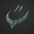 Jewelry set with necklace and earrings featuring green gemstones on a black background