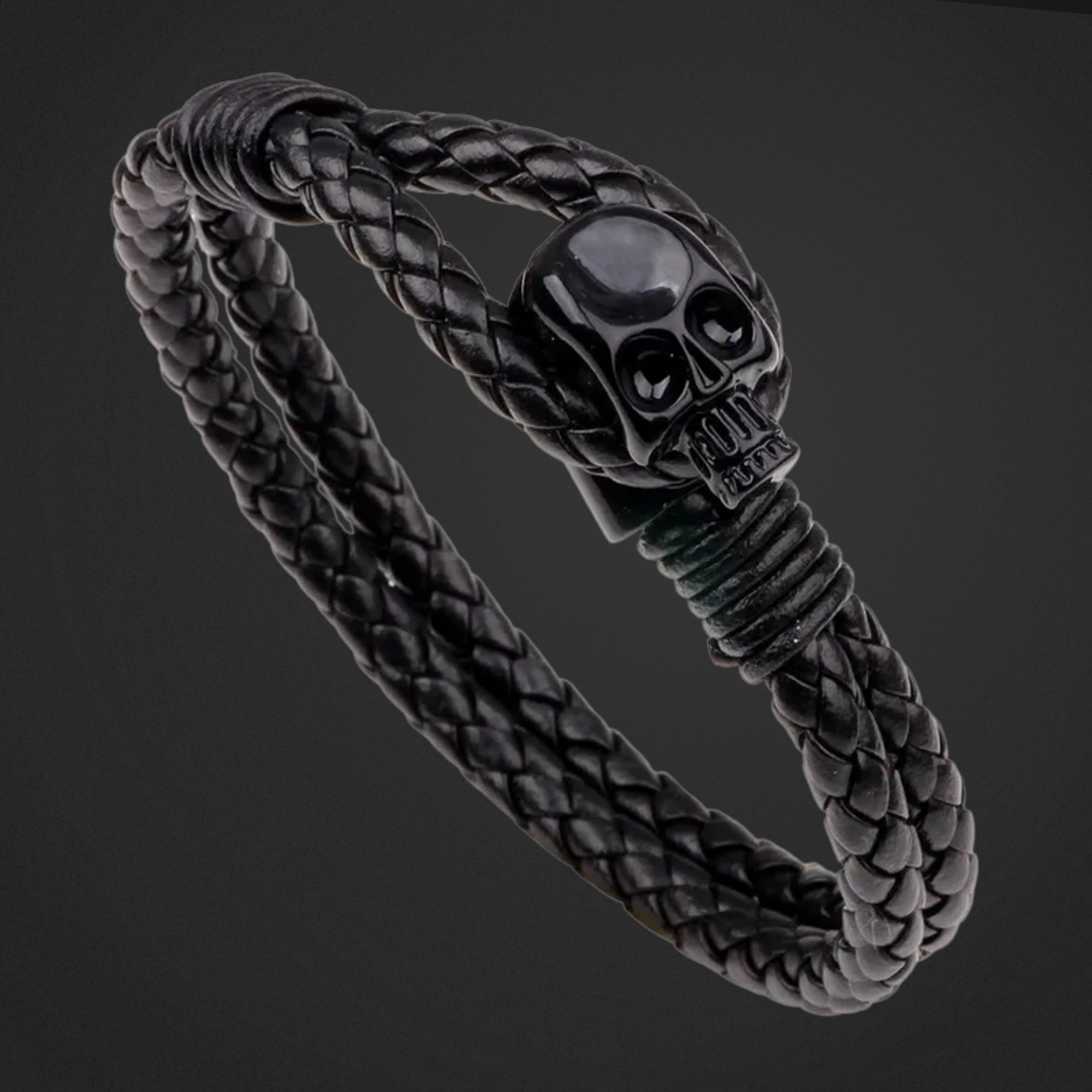 Black braided bracelet with a skull charm on a dark background