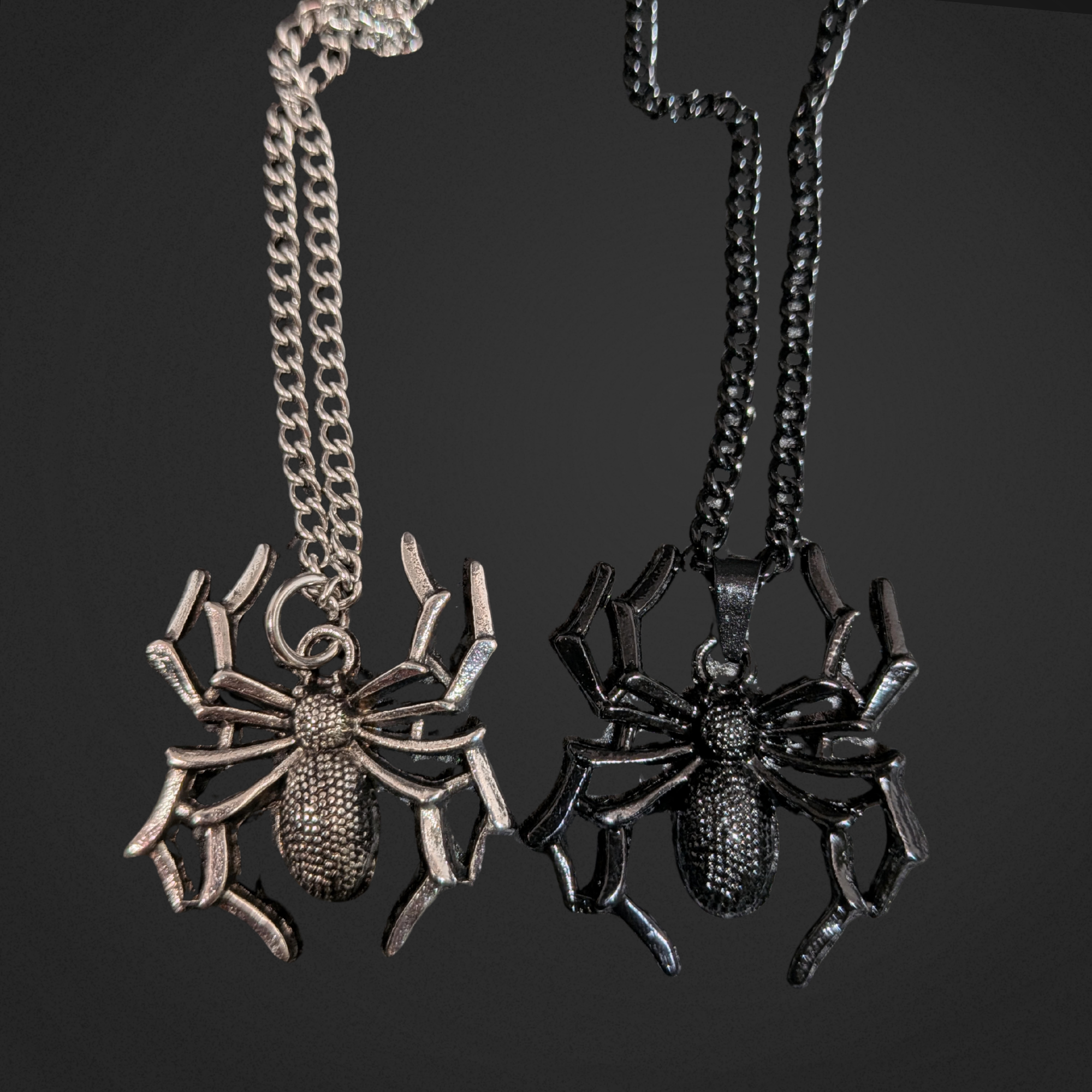 Two spider-shaped pendants on chains against a black background