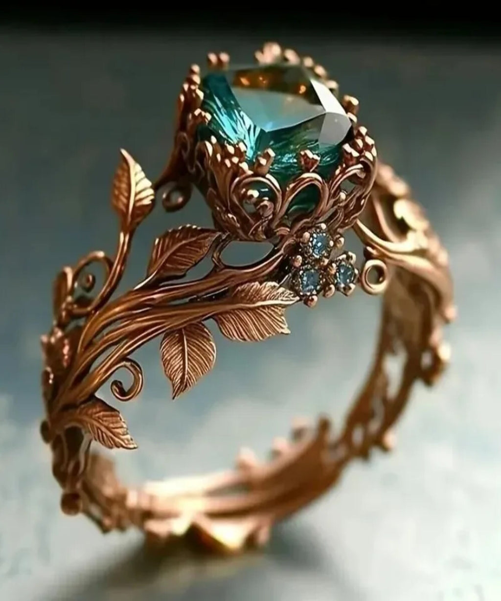Ornate ring with green gemstone and leaf designs on a dark background